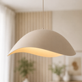 Nami sand taupe wavy metal pendant light lit above a table in a bright room