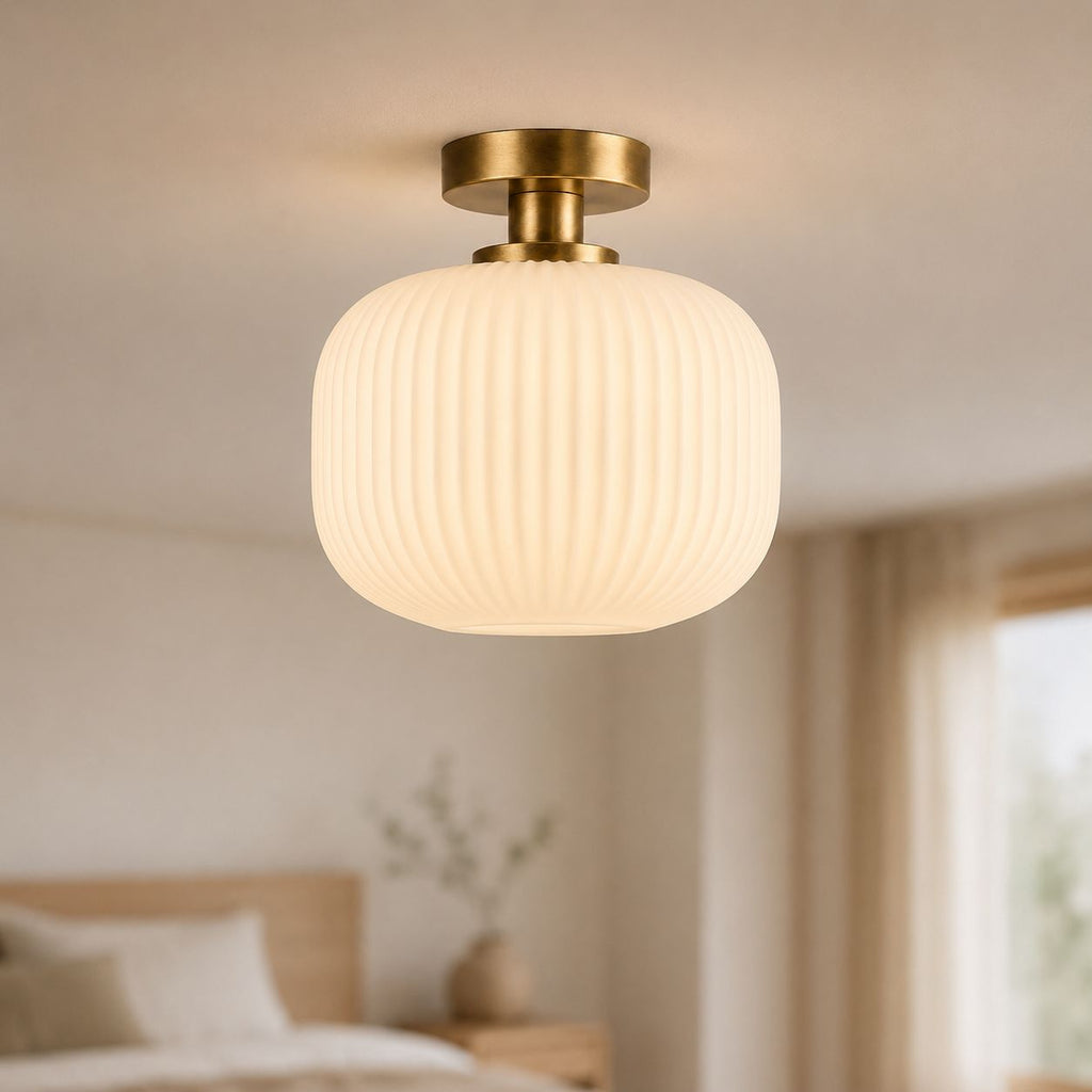 Rivoli antique brass ceiling light with white ribbed opal glass, lit in a living room