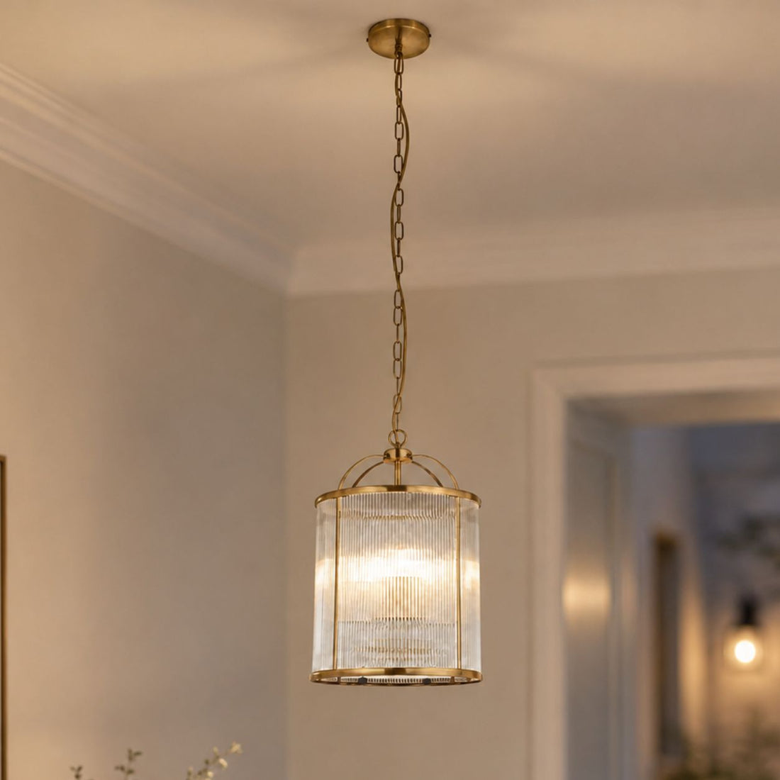 Solene antique brass ribbed glass ceiling pendant on a chain, lit in a hallway