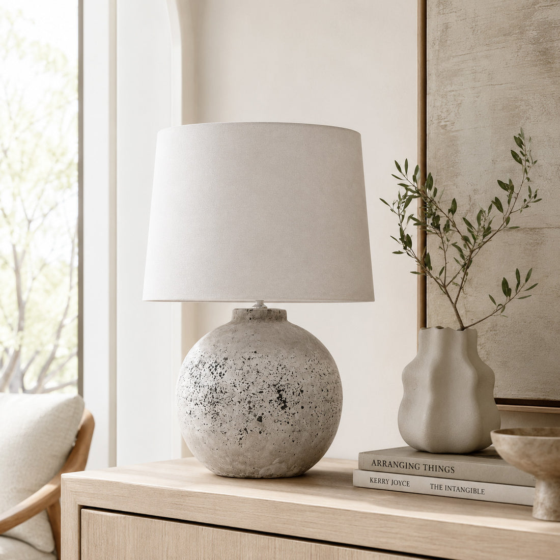 Tiber stone lamp beside a sculptural vase and olive stems on a windowsill console