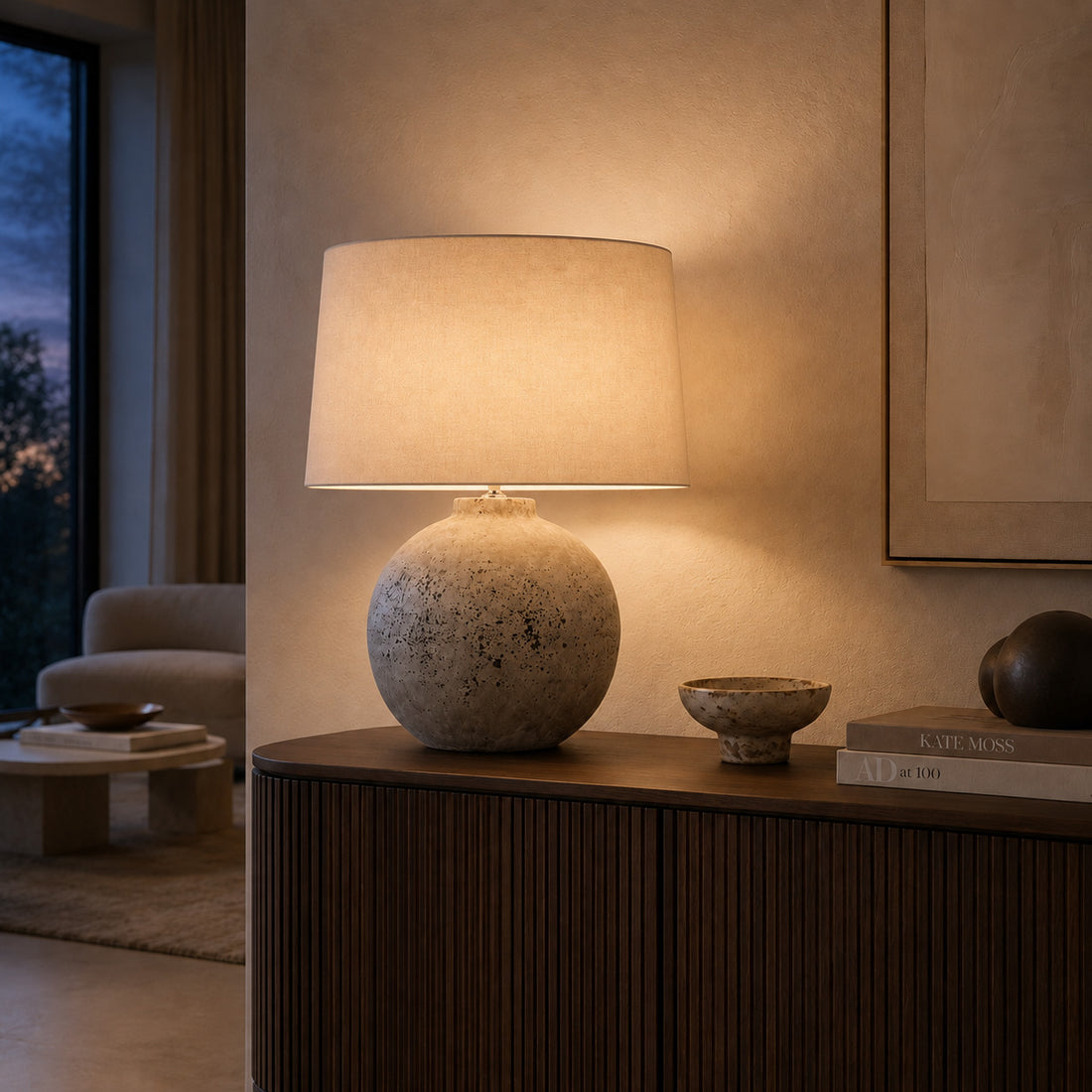 Tiber stone table lamp glowing warmly on a fluted walnut sideboard at dusk