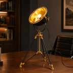 Valen tripod table lamp with black dish shade and brass legs on a desk