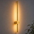 Vireo brushed gold LED stick wall light with ambient backlight glowing on a wall