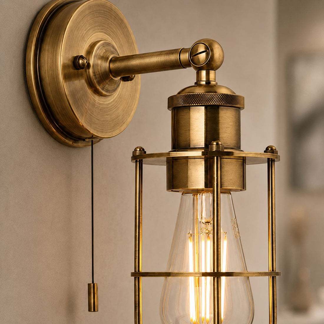 Visby antique brass caged bathroom wall light with pull cord and filament bulb, close-up