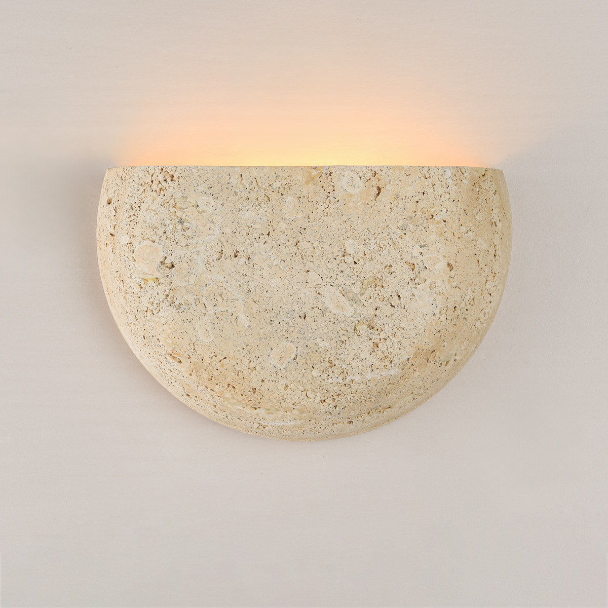 Wara travertine wall light installed in hallway creating ambient wall washing effect