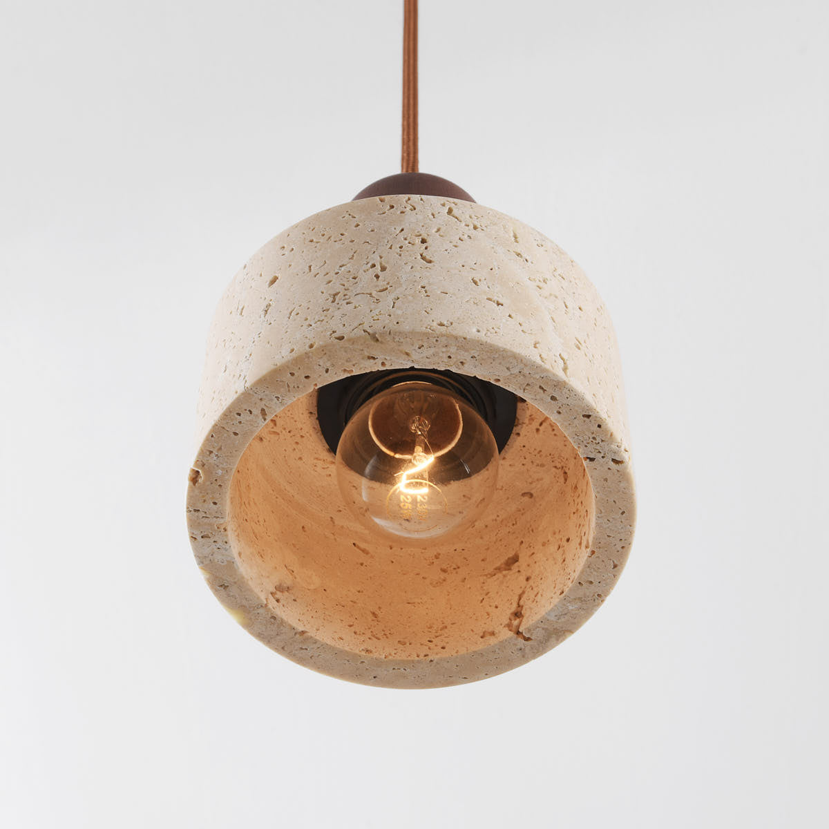 Single travertine pendant light illuminated showing soft ambient glow