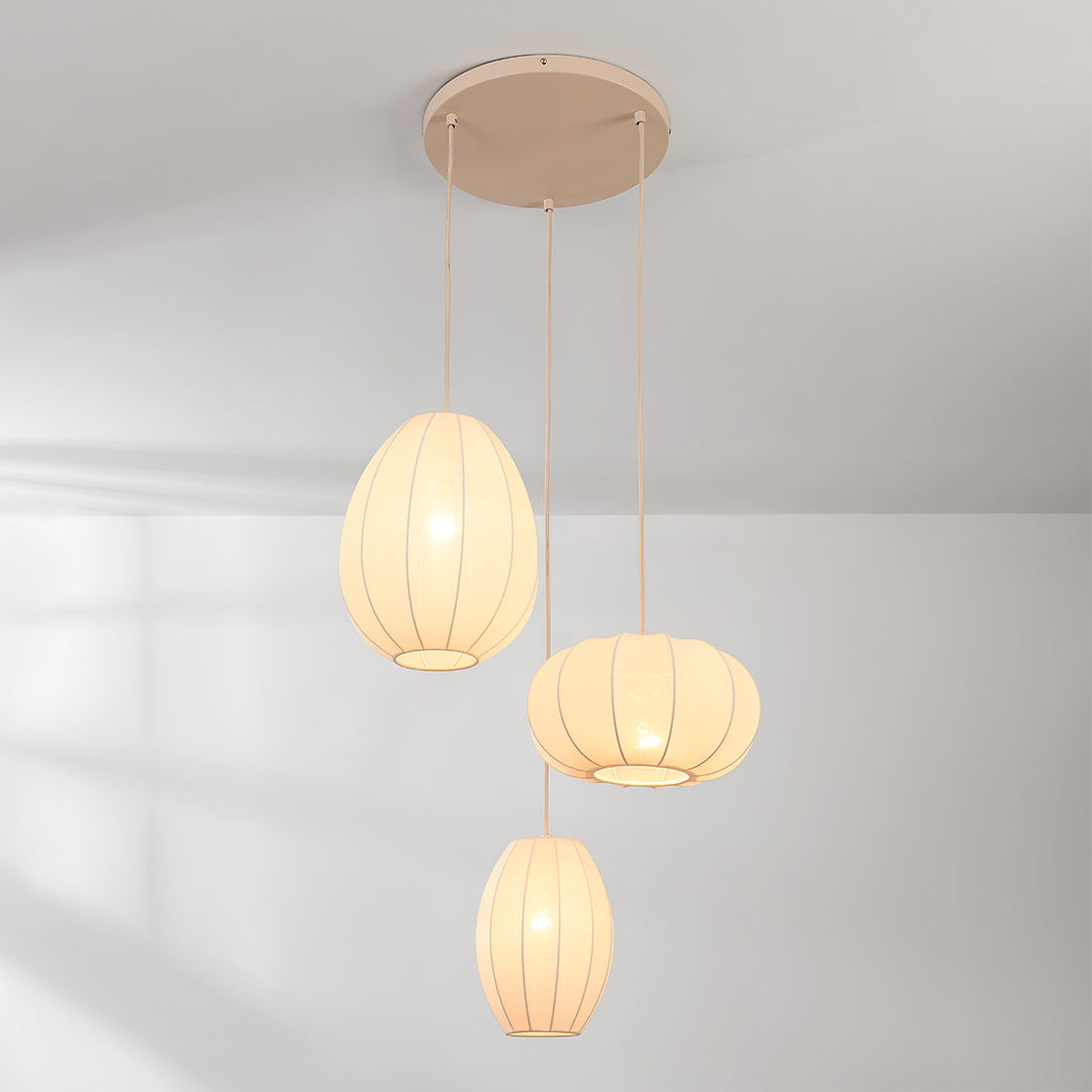 Three staggered fabric pendant lights in warm beige creating ambient lighting
