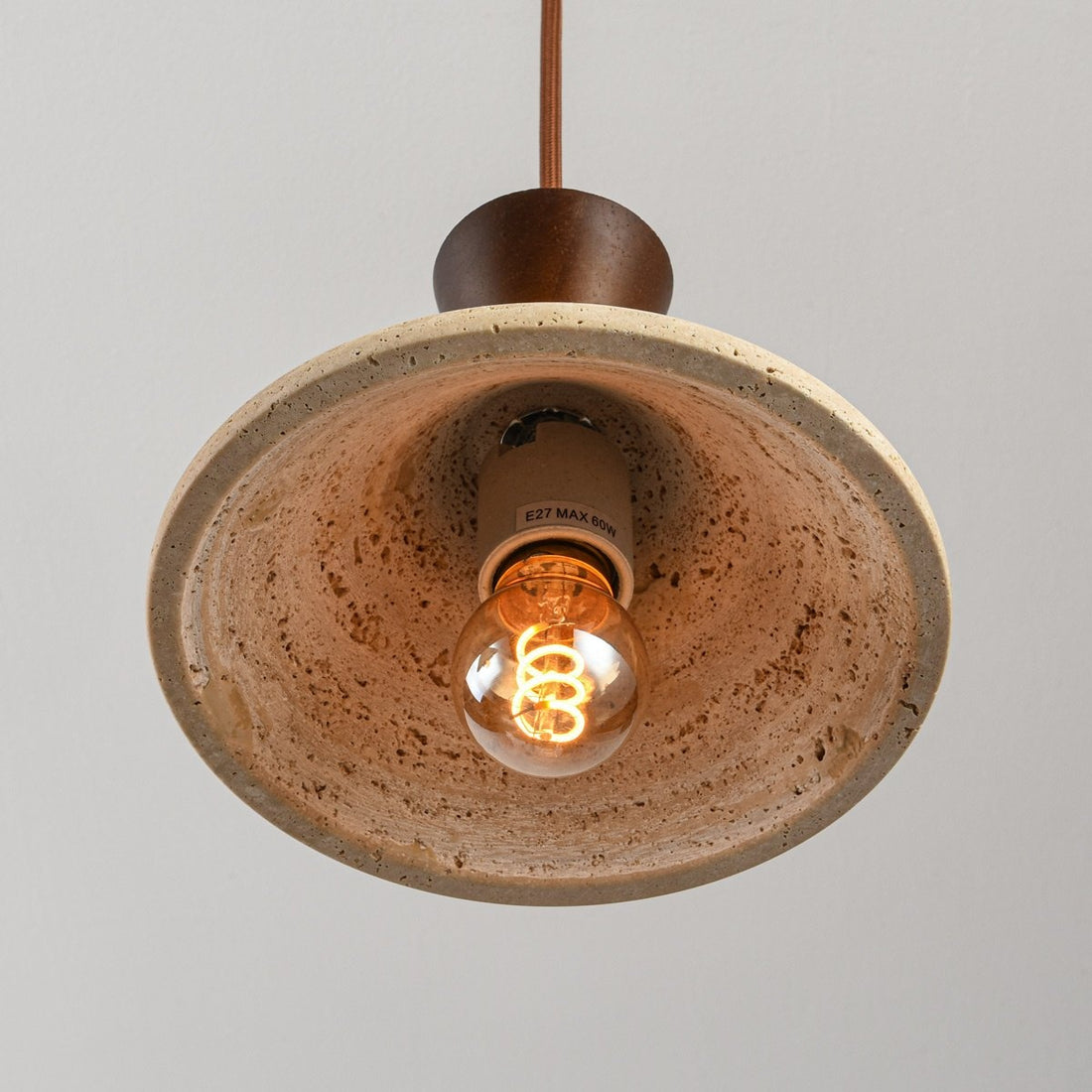 Three light travertine pendant hanging above dining table in UK home