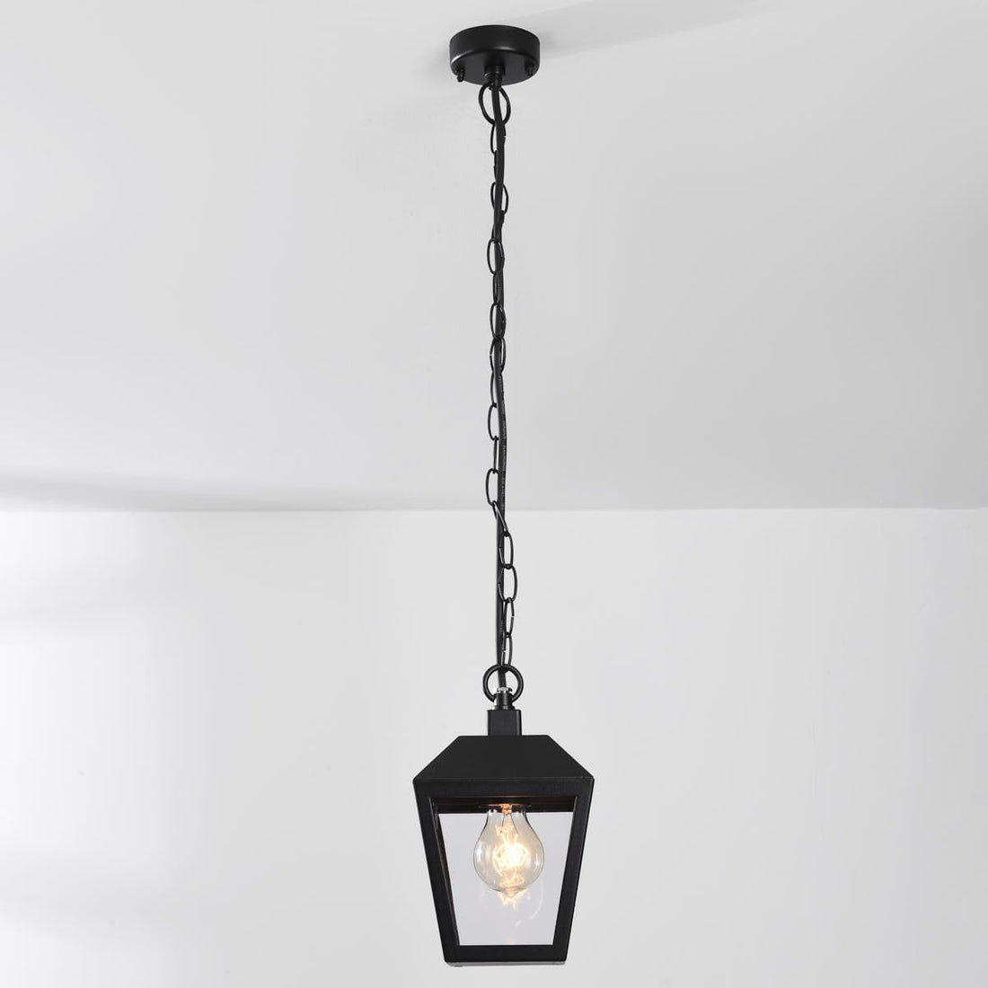 Cairn lantern pendant illuminated on covered patio at evening