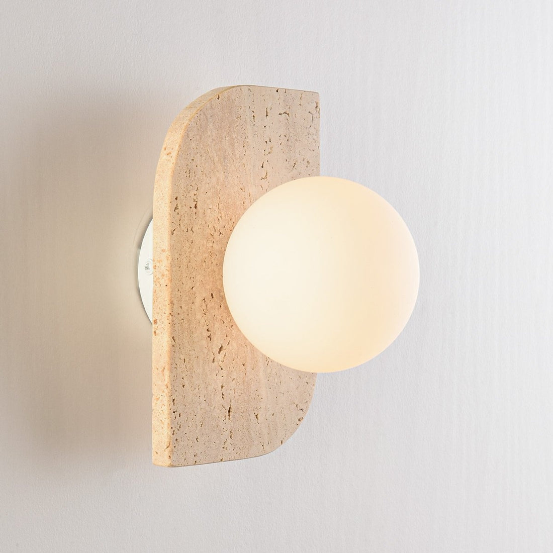 Orla travertine globe wall light with opal glass shade mounted on white wall