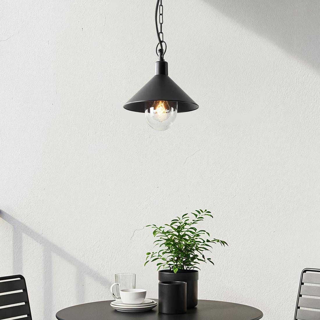 Linden black outdoor pendant light with clear glass globe shade hanging from covered porch