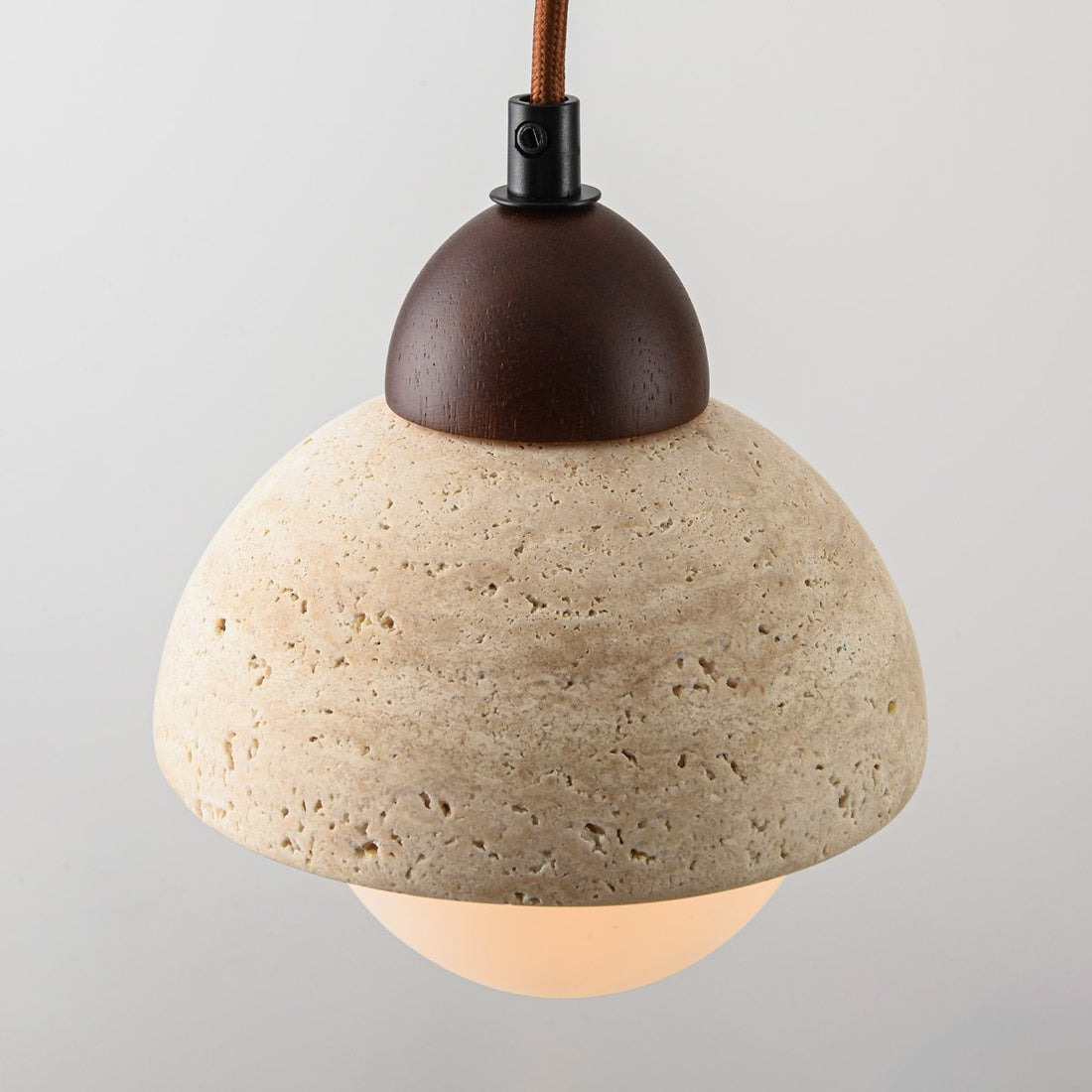 Three light linear travertine pendant suspended over dining table in modern interior