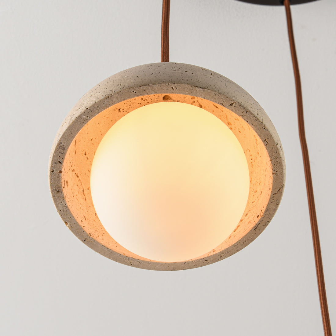 Opale layered pendant light illuminated showing warm glow through travertine and opal glass