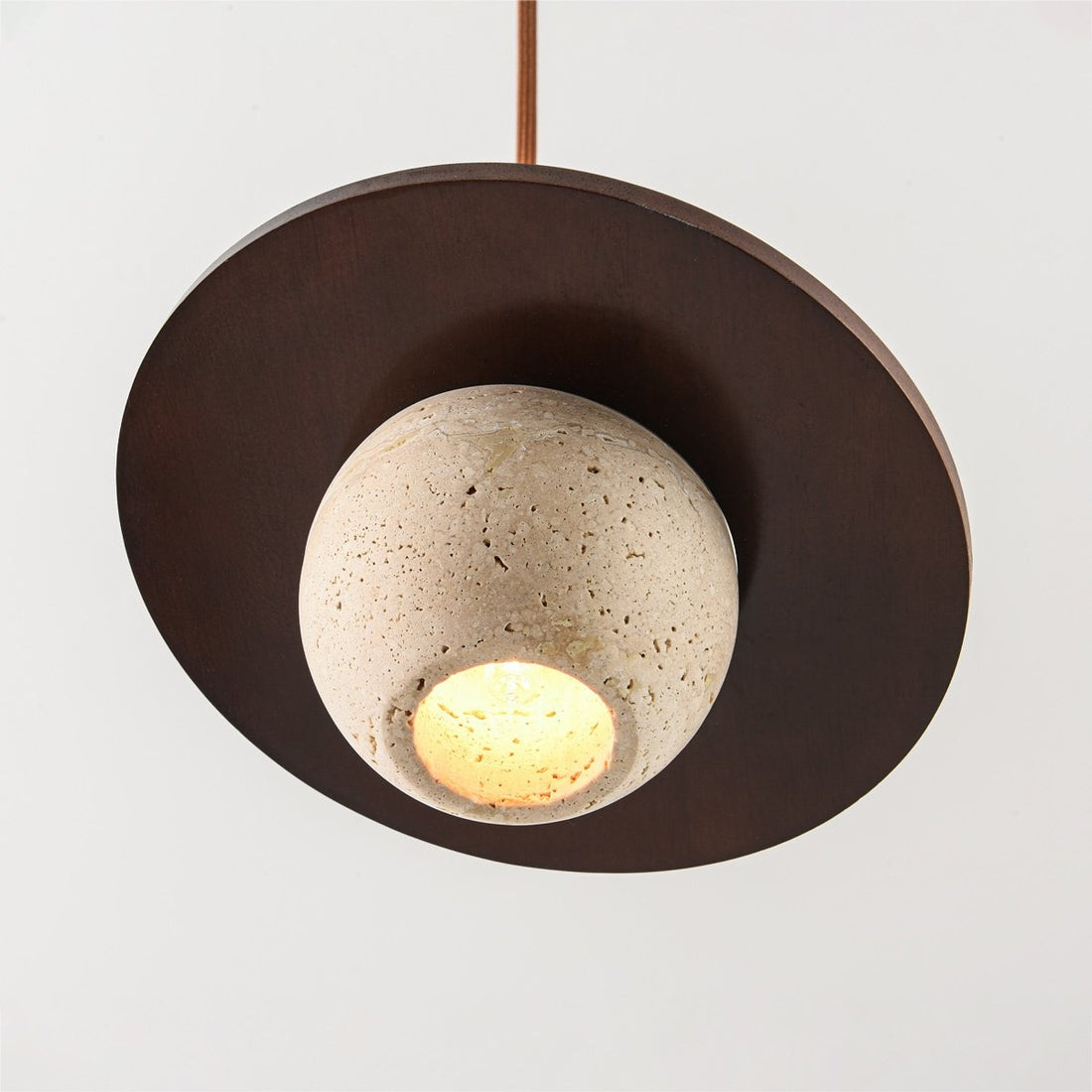 Tomo single pendant light illuminated showing warm light through travertine stone