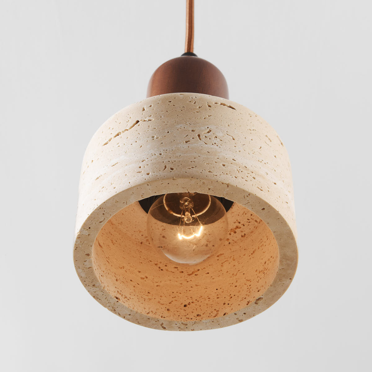 Four light linear travertine pendant light suspended over kitchen island