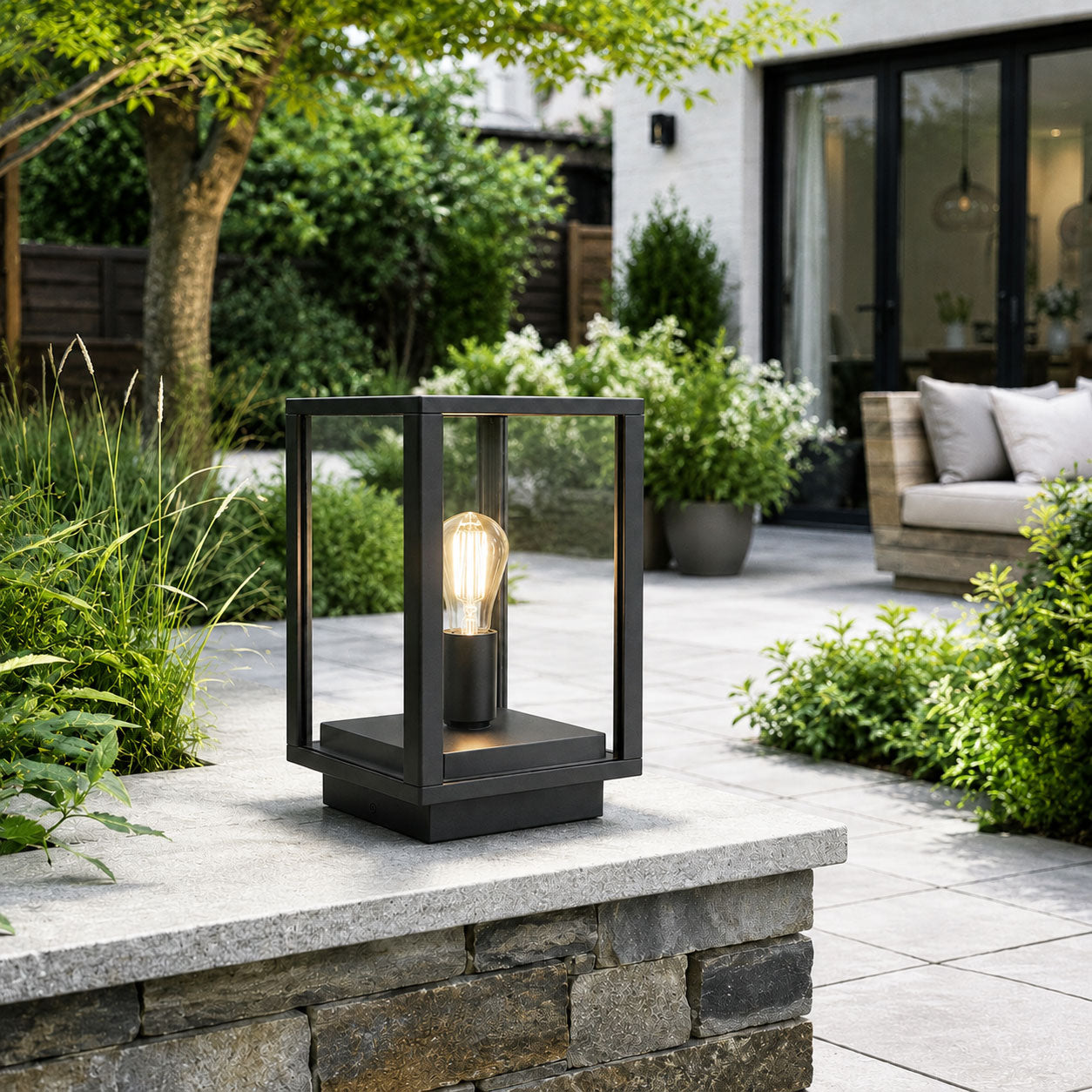 Sem black post lantern on a stone garden wall with hedging and terrace seating