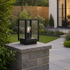 Sem black glass post lantern on a rendered wall pillar with lawn and slatted fence