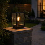 Sem black post lantern lit at dusk on a stone wall in front of a modern house