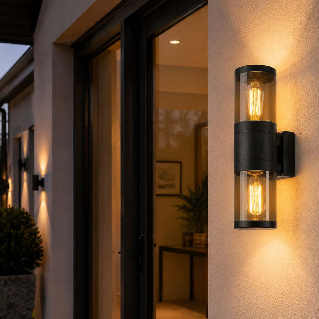 Rouen black up and down wall light lit beside a dark front door at night