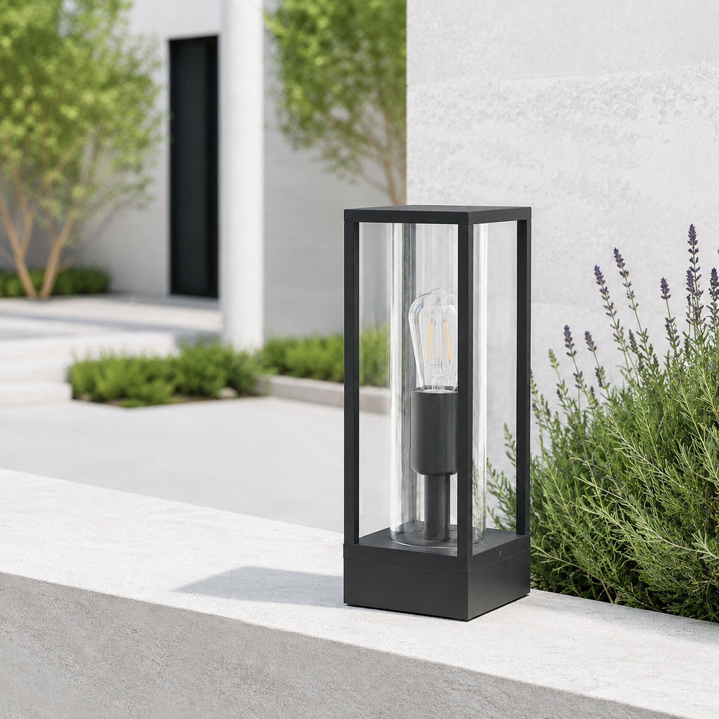 Ted black outdoor post lantern on a white rendered wall with lavender in daylight