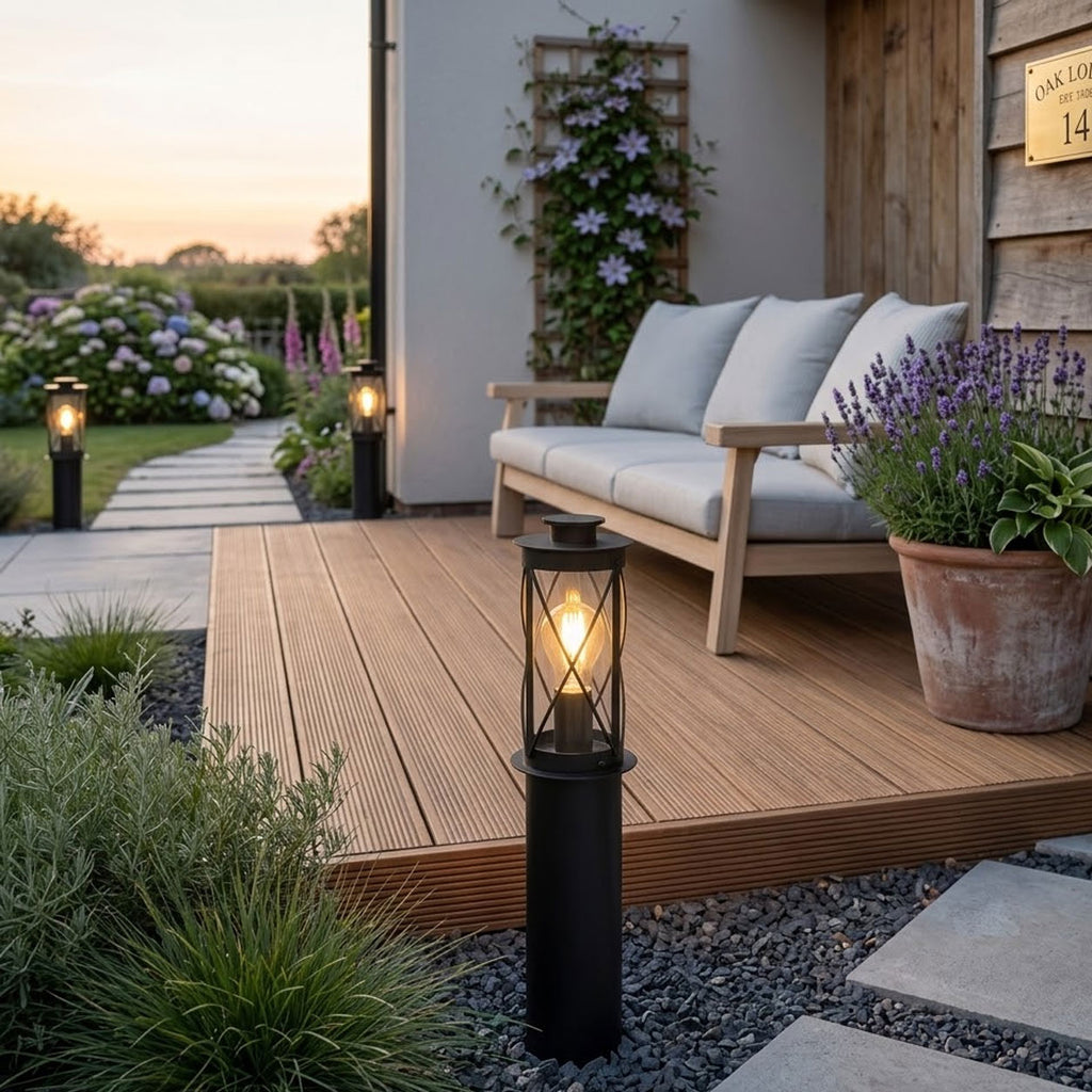 Lucia 40cm black bollard light on decking beside an outdoor sofa and lavender