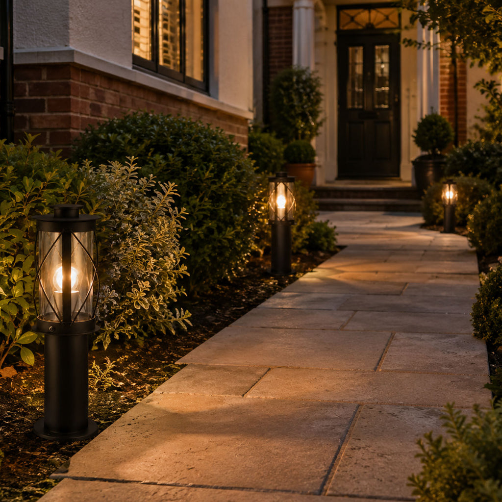 Lucia 40cm black bollard lights lit along a garden path to a front door at dusk