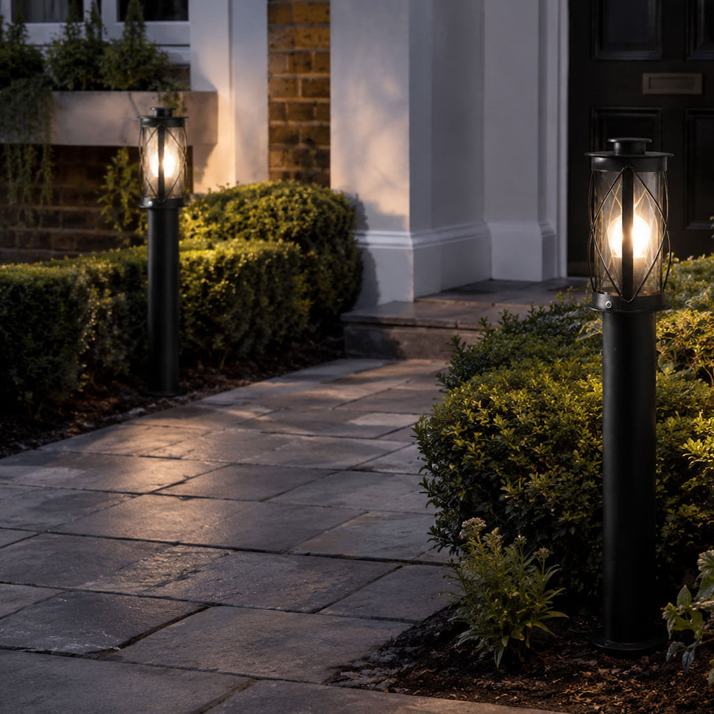 Lucia black bollard post lights lit along a paved front path to a porch at dusk