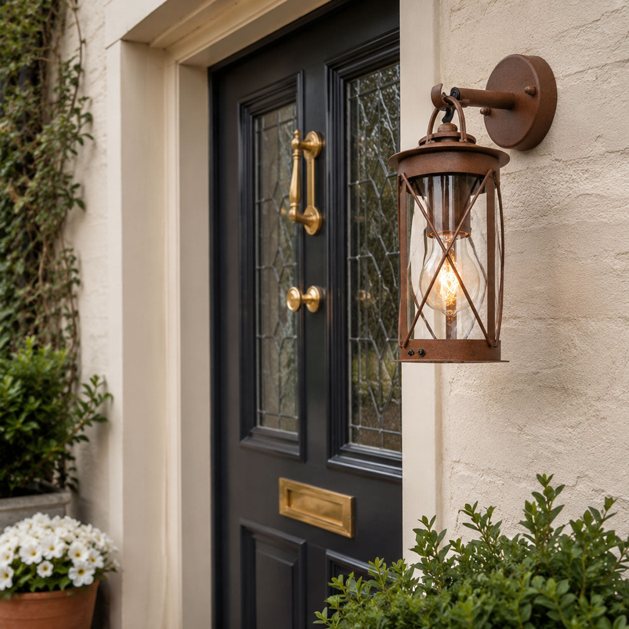 Alicia rust brown farmhouse wall lantern lit next to a black door with brass fittings